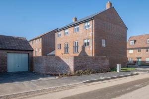a brick building with a garage next to a street at Modern 5 Bedroom 3 Bathroom Serviced House Aylesbury with Parking By 360Stays in Aylesbury