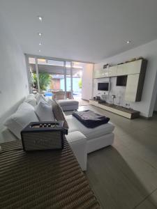 a living room with a white couch and a kitchen at Nosotros Luxury Villa in Los Cristianos