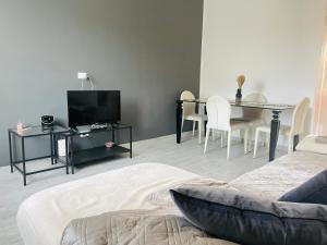 un soggiorno con TV e tavolo con sedie di Appartamento Le Risaie a Vercelli
