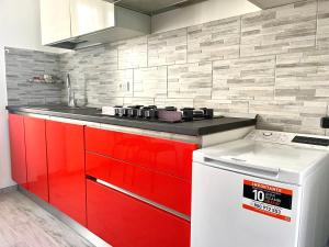 una cucina con armadi rossi e stufa bianca di Appartamento Le Risaie a Vercelli