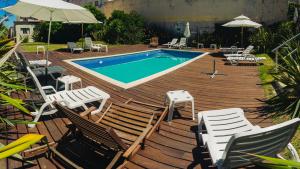 a wooden deck with chairs and a swimming pool at Hotel Milano in Punta del Este