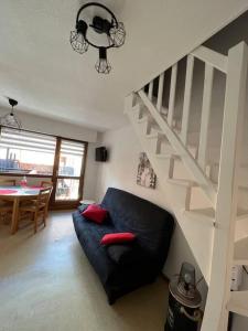 a living room with a black couch and a staircase at Appartement duplex avec vue sur le domaine skiable in Le Grand-Bornand