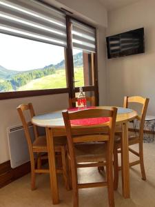 stół jadalny z krzesłami i oknem w obiekcie Appartement duplex avec vue sur le domaine skiable w mieście Le Grand-Bornand