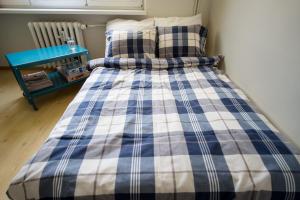 a bed with a blue and white plaid blanket at Studio Centrum in Gdynia