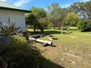 a yard with a house and a pile of logs at Bush Retreat Farm Stay 2 BR in Gelliondale