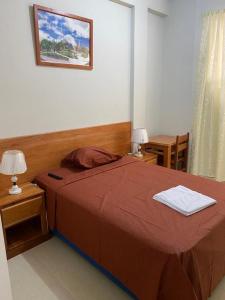 a bedroom with a large bed with a red blanket at Alojamiento Everglow in Iquitos