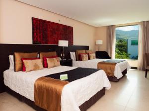a hotel room with two beds and a large window at Studio Hotel Boutique in San José