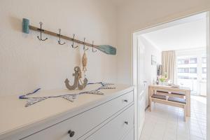 eine weiße Küche mit einer Theke und einem Tisch in der Unterkunft Ferienwohnungen im Haus Strandburg Grömitz in Grömitz + 37 Fotos