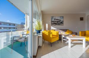 ein Wohnzimmer mit einem gelben Stuhl und einem Tisch in der Unterkunft Ferienwohnungen im Haus Strandburg Grömitz in Grömitz