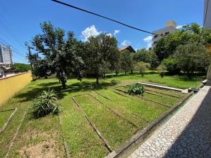un jardín con césped y árboles en el lateral de un edificio en Casa da Vovó, en Itapema