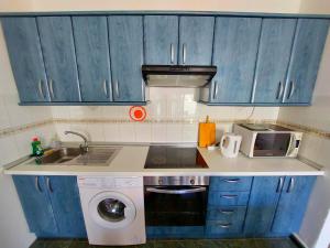 cocina pequeña con armarios azules y lavadora en Casa Azul, en Costa de Antigua