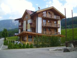 a large wooden house on top of a hill at Hotel Garnì Il Giglio in Commezzadura