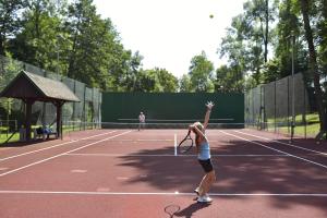 a woman serving a tennis ball on a tennis court at MIESZKANIE w Centrum PRZY PROMENADZIE i JEZIORZE Stare Miasto!!! Parking ! in Mrągowo