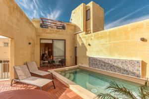 une maison avec une piscine et deux chaises dans l'établissement Narcisa - Luxury 3BR Traditional House with Pool, Cinema & Hot Tub, à Tal-Barmil