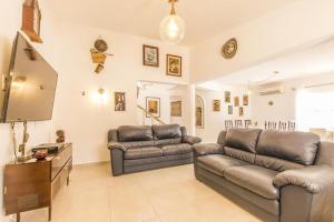Sala de estar con 2 sofás de cuero y TV en Villa Saudade, en Lagoa