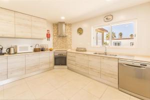 a large kitchen with wooden cabinets and a window at Villa Saudade in Lagoa