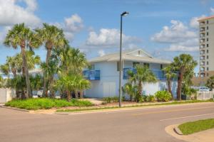 a white house with palm trees in front of a street at Once Upon A Tide Oceanview Condo Pet Friendly in Jacksonville Beach