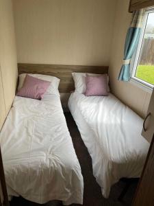 two beds in a small room with two pillows at Withersea Sand Holiday Home in Withernsea