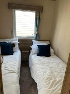 two beds in a small room with a window at Withersea Sand Holiday Home in Withernsea