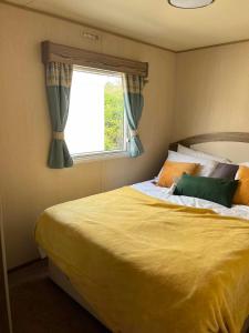 a bedroom with a large bed with a window at Withersea Sand Holiday Home in Withernsea