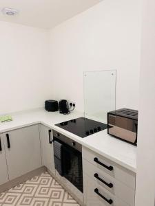 a white kitchen with a stove and a microwave at City Blessed Apartment 1 with free parking in North Shields
