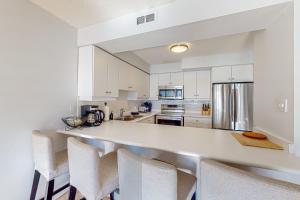 a kitchen with white cabinets and a counter with chairs at Chateau Ridge 223 in Blue Mountains