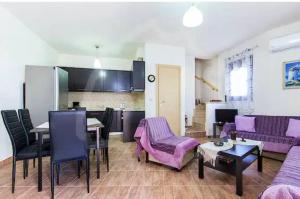 a living room with purple furniture and a kitchen at Villa Armonia in Skala Potamias