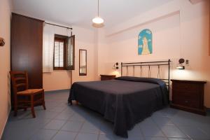 ein Schlafzimmer mit einem Bett und einem Stuhl in der Unterkunft La Chiusa Case Vacanze in Castellammare del Golfo