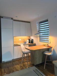 une cuisine avec des placards blancs et un comptoir en bois dans l'établissement Apartman LENA, à Bjelašnica