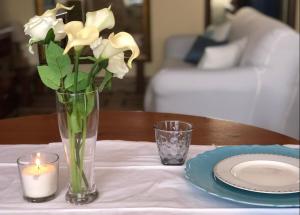 a vase with white flowers and a candle on a table at Apartment Domu Franziska - Beach & City Holiday in Cagliari