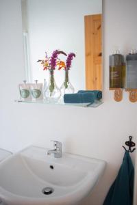 un lavandino in bagno con fiori in vaso su una mensola di Carleys Cottage a Fanore