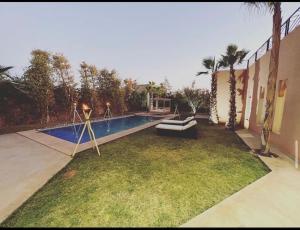 a backyard with a swimming pool with a couch in the grass at Villa aquaparc piscine chauffée sans vis à vis in Marrakesh