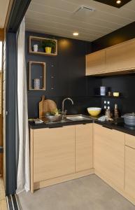 - une cuisine avec des murs noirs, des placards en bois et un évier dans l'établissement Camping Beau Rivage, à Navarrenx