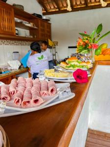 un mostrador con platos de comida y gente en una cocina en Pousada Casa Sítio Delícia do Quadrado, en Porto Seguro