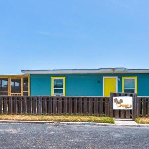 ein blaues Haus mit gelben Türen und einem Holzzaun in der Unterkunft Barefoot Bungalow SPV26 in Port Aransas