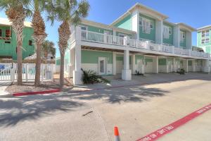 a green building with palm trees in front of it at Barefoot Retreat MC15 in Port Aransas