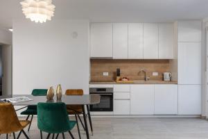 a kitchen with white cabinets and a table with green chairs at Apartments Cesare in Nin