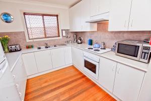 a kitchen with white cabinets and a microwave at Emaroo Cottages Broken Hill in Broken Hill