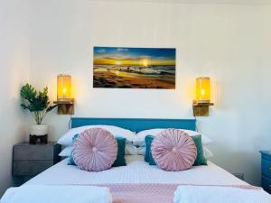 a bedroom with a bed with pink and blue pillows at Palms34 5 minute walk to beach Bungalow in Westward Ho