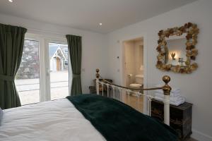 een slaapkamer met een bed met een spiegel en een raam bij Capercaillie Cottage - Luxury converted steading in Perth