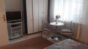 un soggiorno con tavolo, sedie e televisione di Apartman centar Vrbas a Vrbas