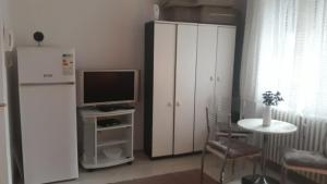 un soggiorno con frigorifero, televisione e tavolo di Apartman centar Vrbas a Vrbas