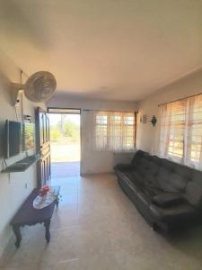 a living room with a black couch and a tv at Jilymar Cabaña de descanso, Isla de Barú - Cartagena in Santa Ana