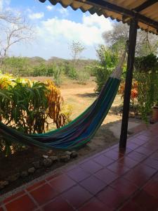 a hammock on a porch with a view of a field at Jilymar Cabaña de descanso, Isla de Barú - Cartagena in Santa Ana