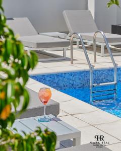 a drink sitting on a table next to a swimming pool at Plaza Real Suites Hotel in Rosario
