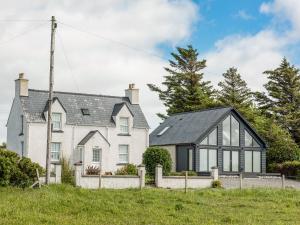 een groot wit huis met zwarte ramen bij Shore Lodge in Stornoway