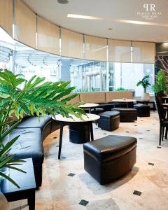 a lobby with tables and chairs and plants at Plaza Real Suites Hotel in Rosario