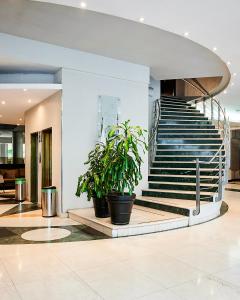 a lobby with a staircase and two potted plants at Plaza Real Suites Hotel in Rosario