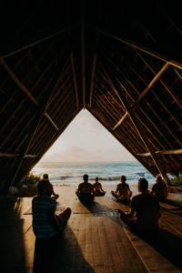 een groep mensen die op het strand zitten en naar de oceaan kijken bij Papaya Playa Project in Tulum