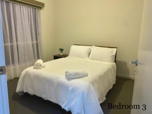 een slaapkamer met een wit bed en handdoeken bij Gardens Vista Villa in Lyndhurst